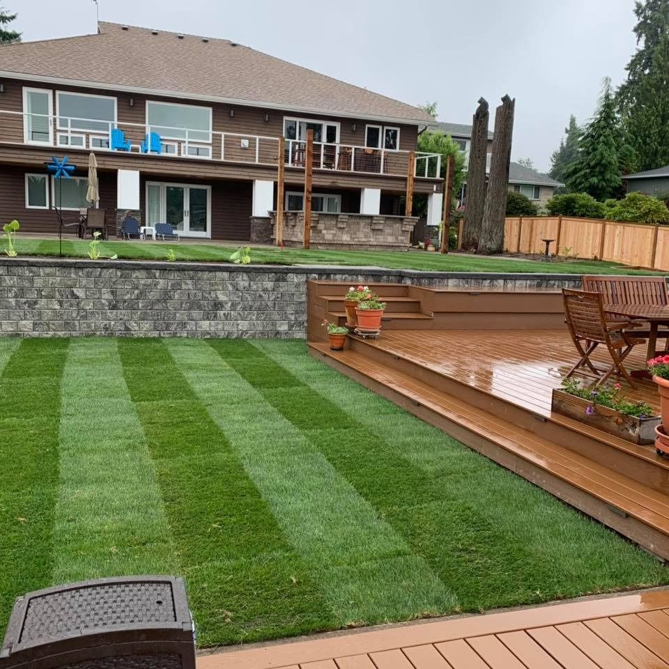 Well-manicured backyard with striped lawn, raised deck, and a two-story house in the background.