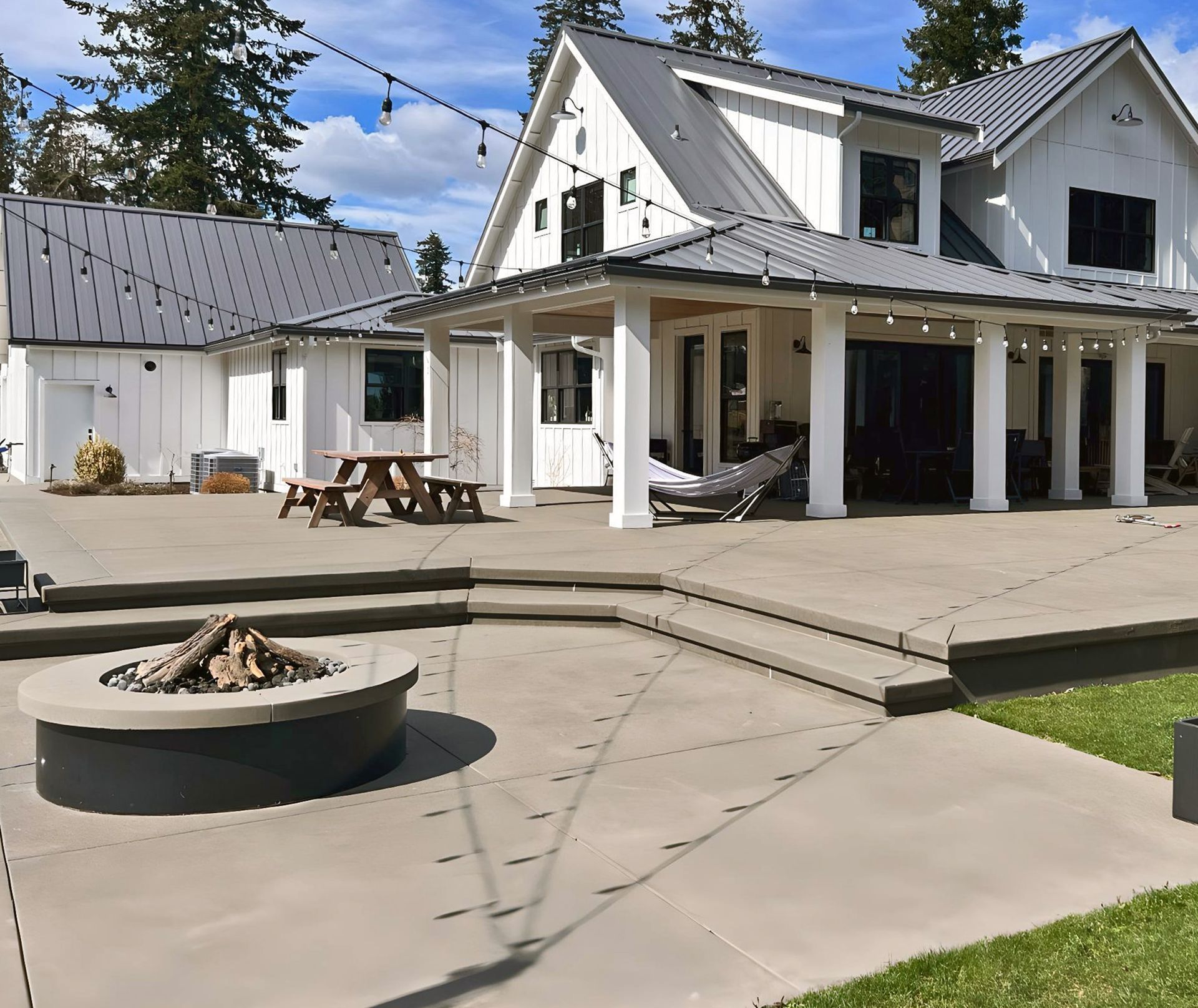 Night view of a house with illuminated driveway and landscaping; trees and stars visible in the background.