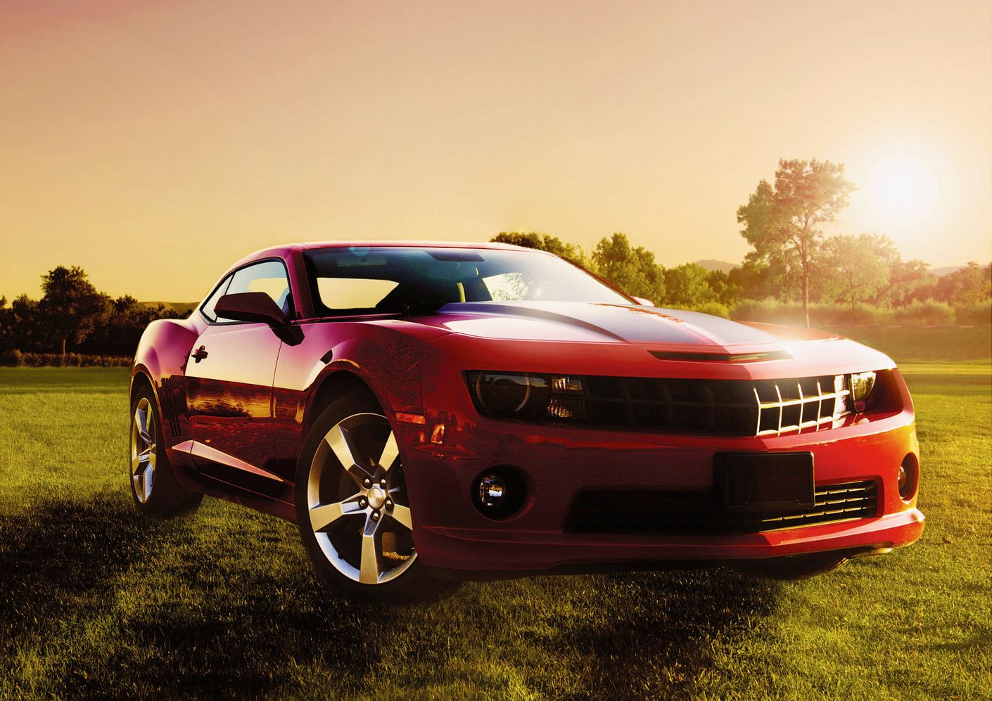 Red sports car parked on grass at sunset with warm golden light