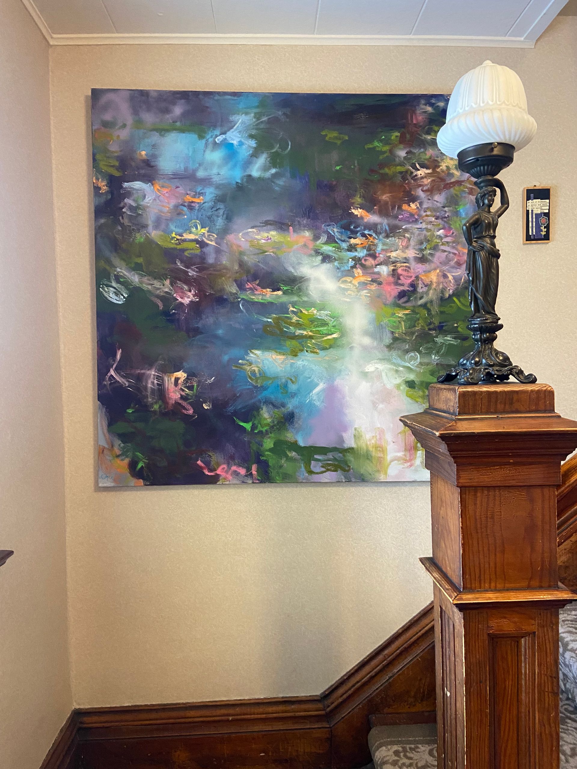 There is a large painting on the wall above the stairs.