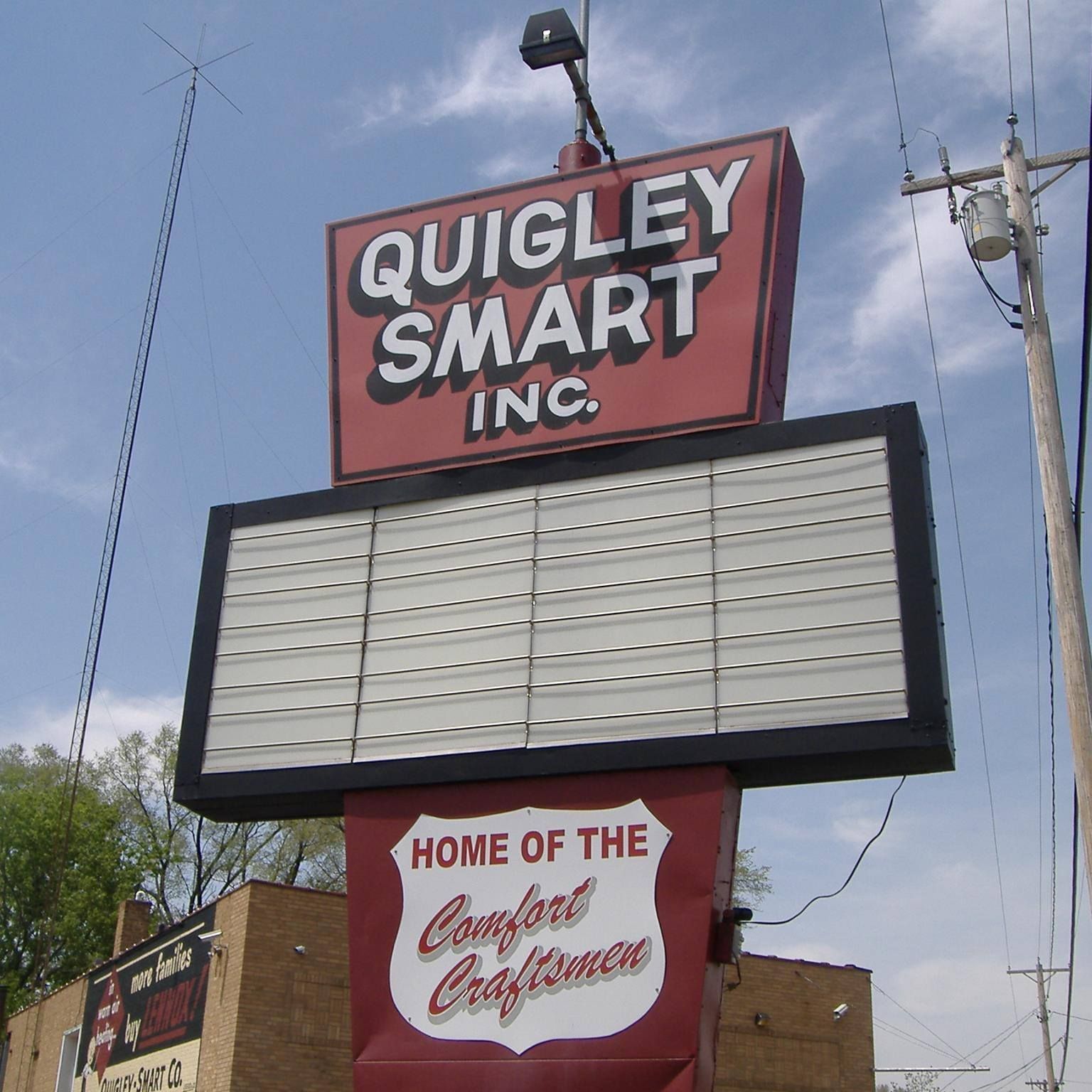 A sign for quigley smart inc. says home of the comfort craftsman.