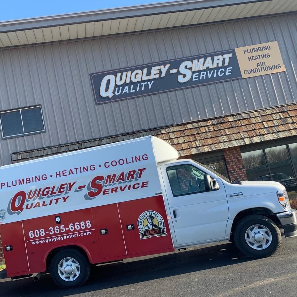A quigley smart service truck is parked in front of a building.