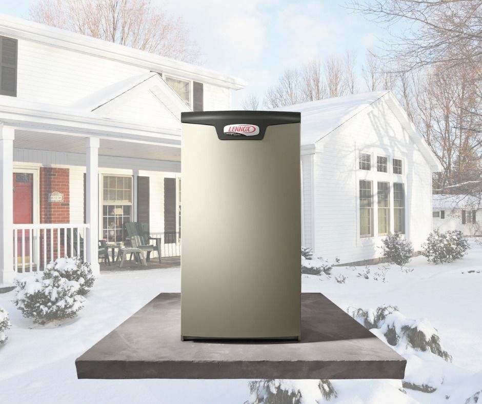 A lennox air conditioner is sitting in front of a snowy house.