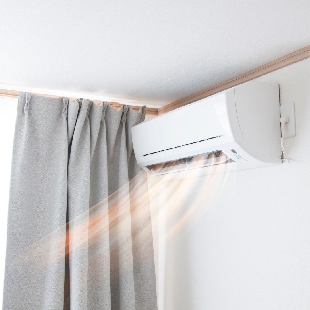 A white air conditioner is hanging from the ceiling next to a window.