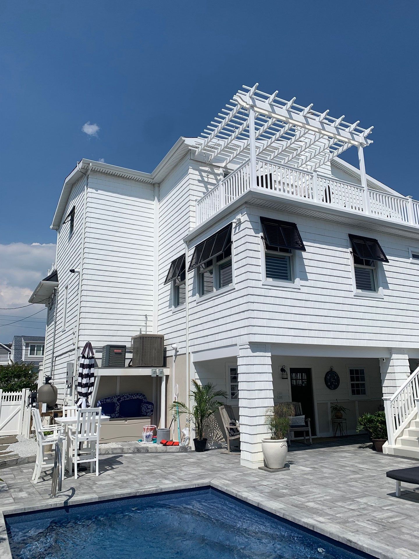 white 3-story house with pool and shutters