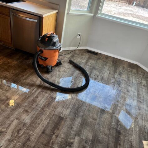 Orange wet/dry vacuum on a wood floor in a bright room near a window