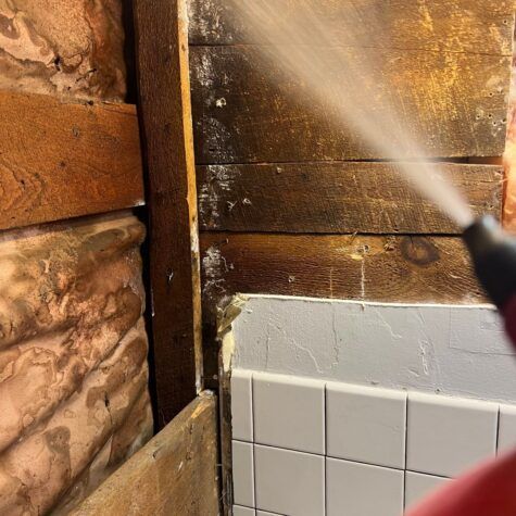 Spraying a rustic wall and white tile surface with water or cleaner