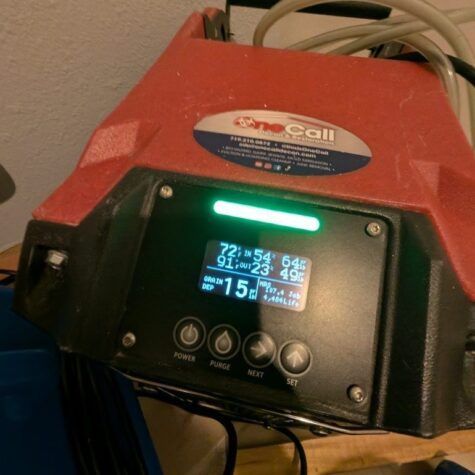 Red and black pool controller with a glowing digital display and buttons, mounted with cables behind it
