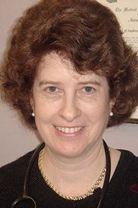 A woman is wearing a stethoscope around her neck and smiling.