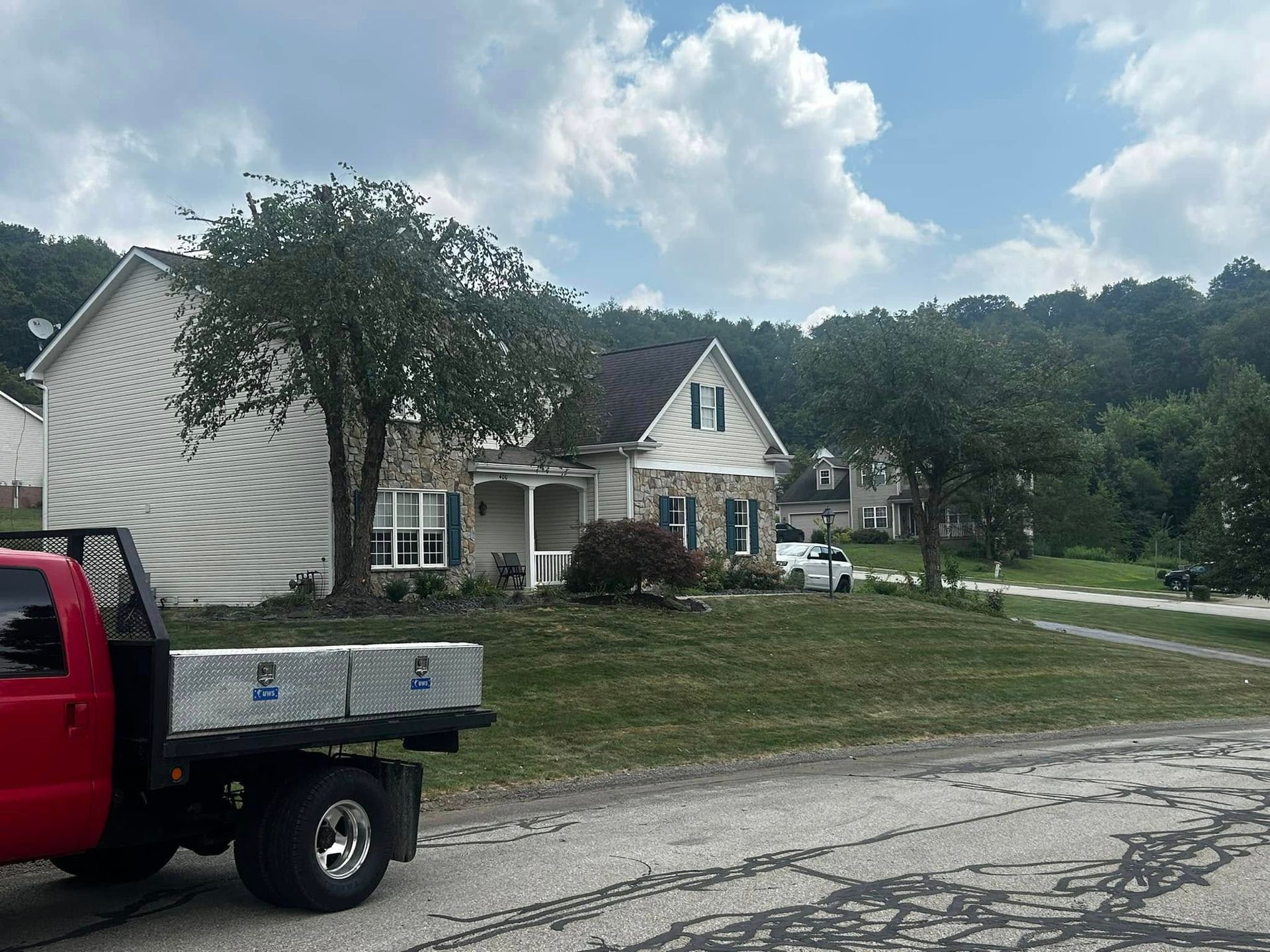 Suburban house with a truck parked by the road under a partly cloudy sky
