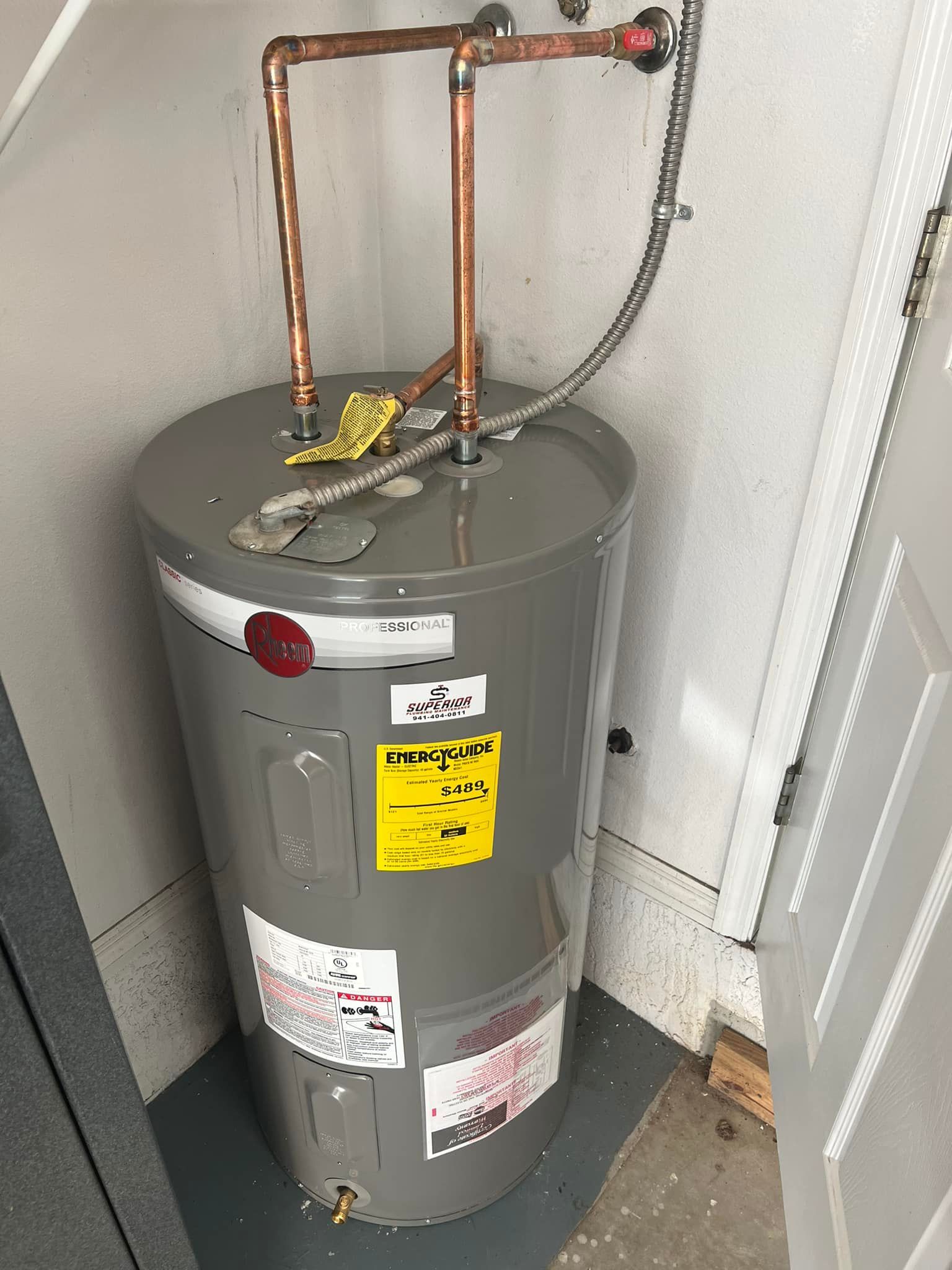 Gray water heater with copper pipes in a utility closet.