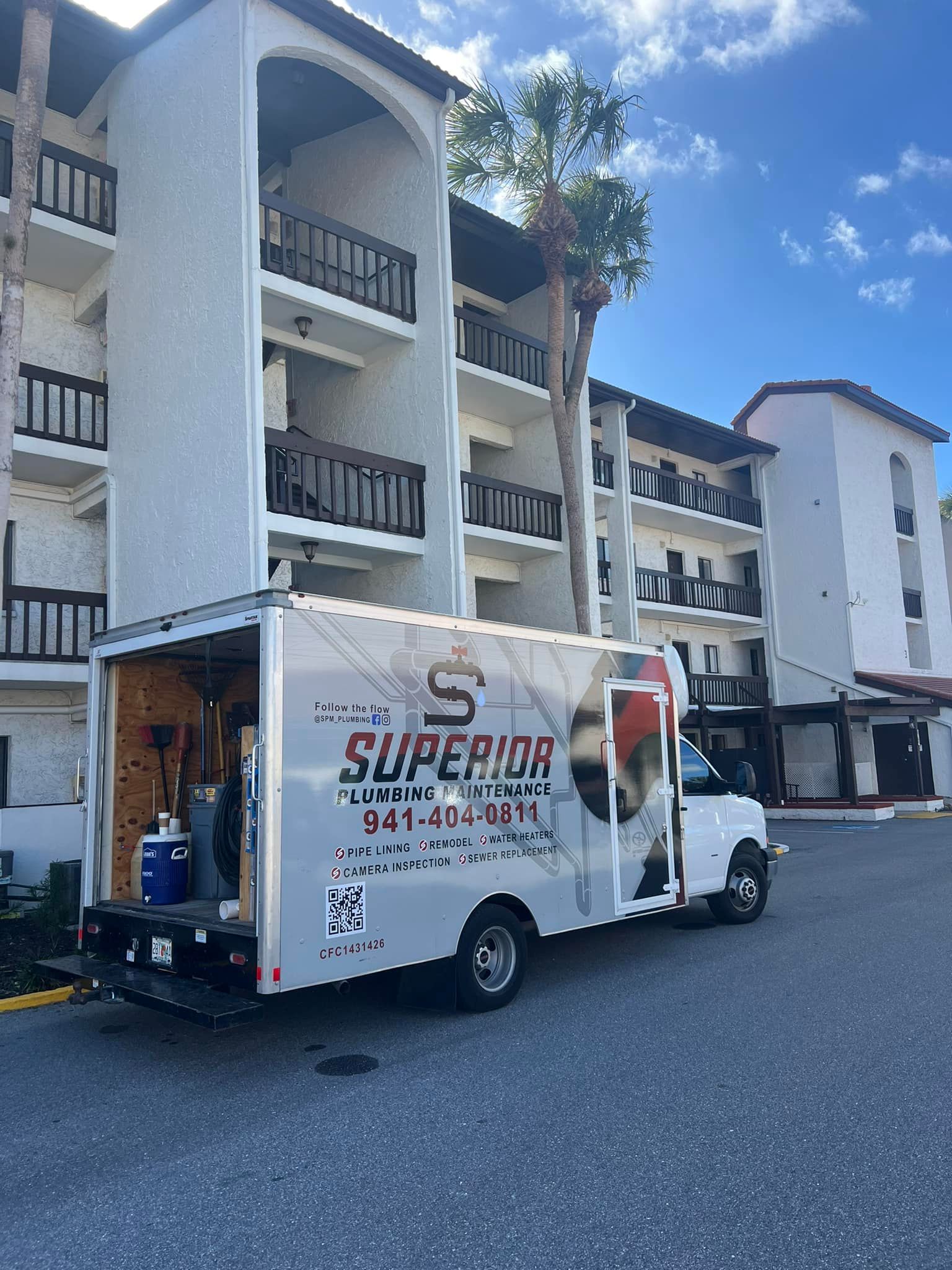 A white Superior Moving truck parked in front of a multi-story building. The truck door is open.