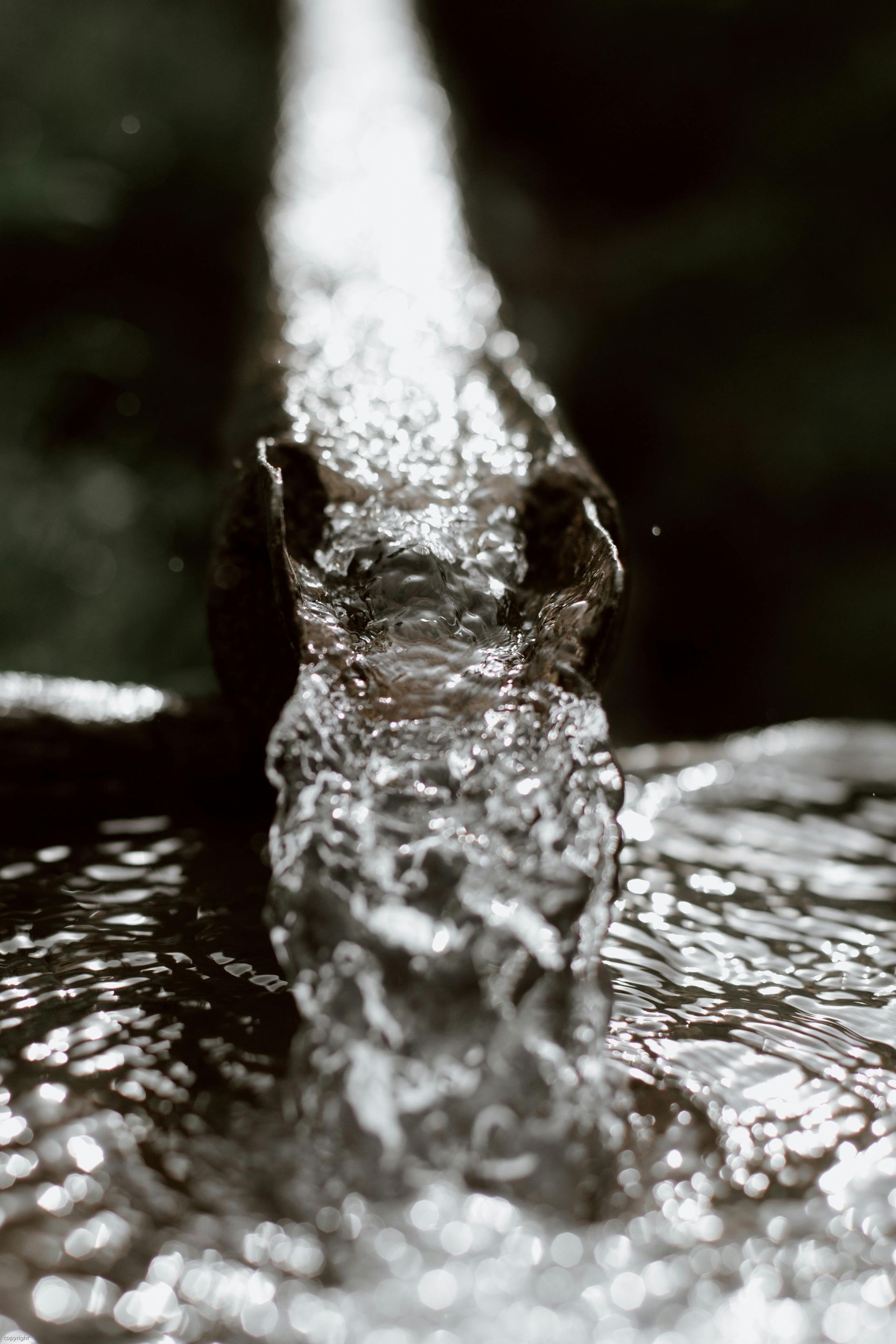 Water flowing from a faucet, with close-up view of the stream.
