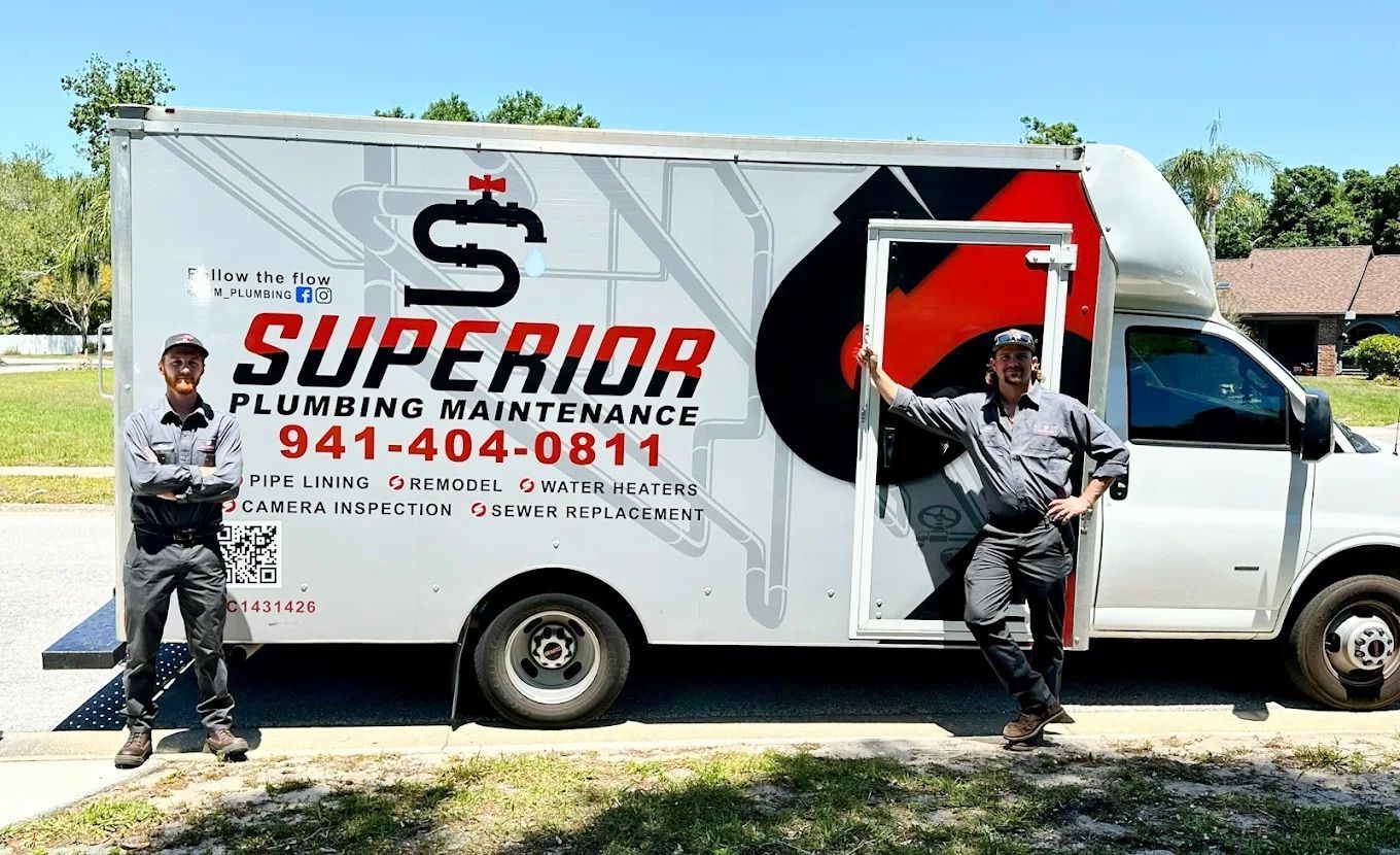 Two men stand beside a white plumbing truck with "Superior Plumbing Maintenance" logo and phone number.