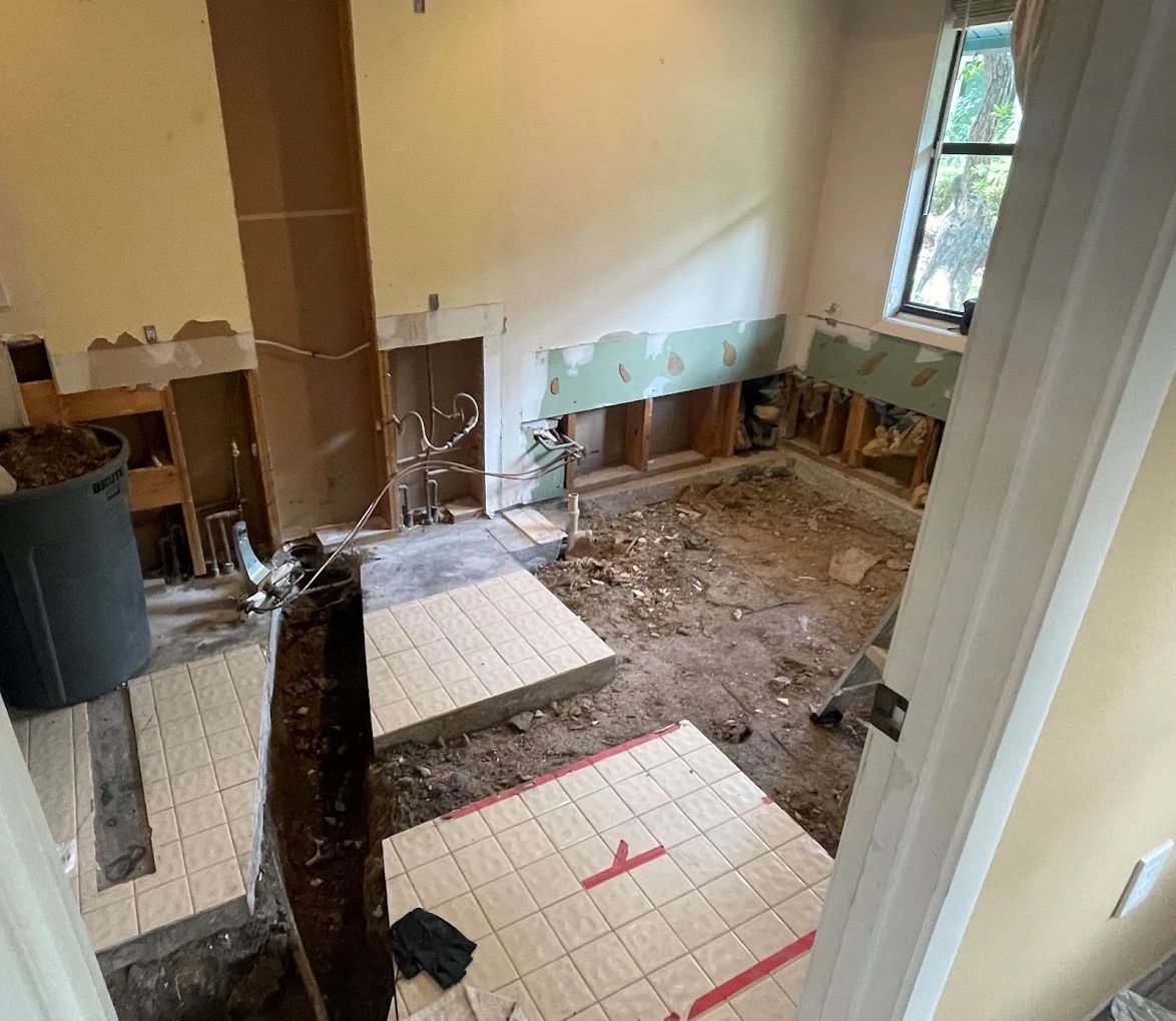 Room renovation in progress, walls stripped to studs. Insulation and debris on the floor.