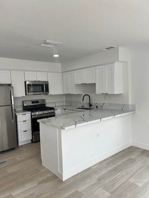White kitchen with stainless steel appliances, light countertops, and a central island.