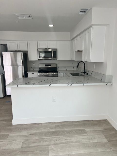 White kitchen with stainless steel appliances and marble countertops.