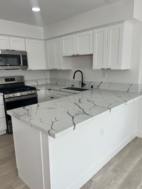 White kitchen with quartz countertops, white cabinets, and stainless steel appliances.