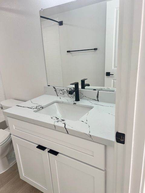 White bathroom with a marble-look countertop, black fixtures, and a white vanity.