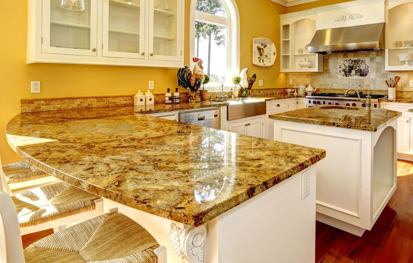 Golden-toned kitchen with granite countertops and white cabinets, including a central island and a sunny window.