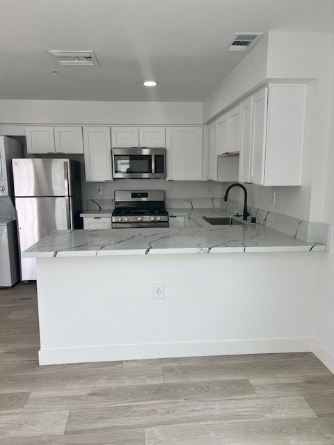 White kitchen with stainless steel appliances and marble countertops.