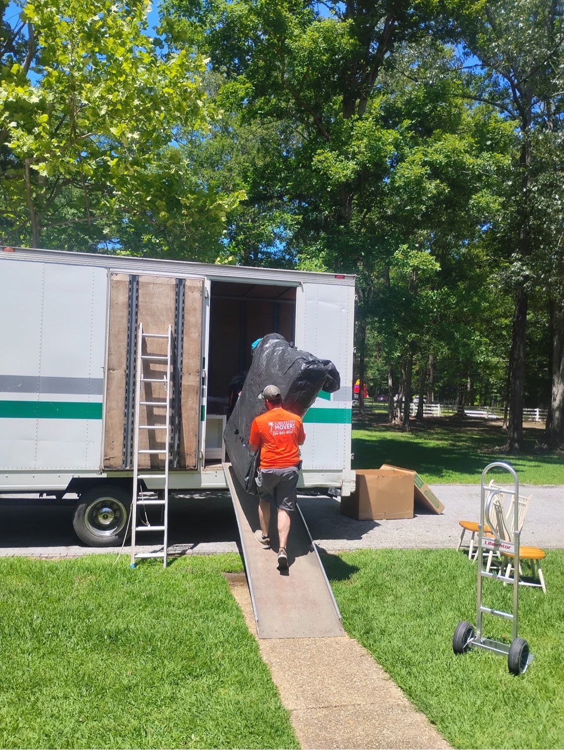 Person pushing a furniture up a ramp into a white moving truck