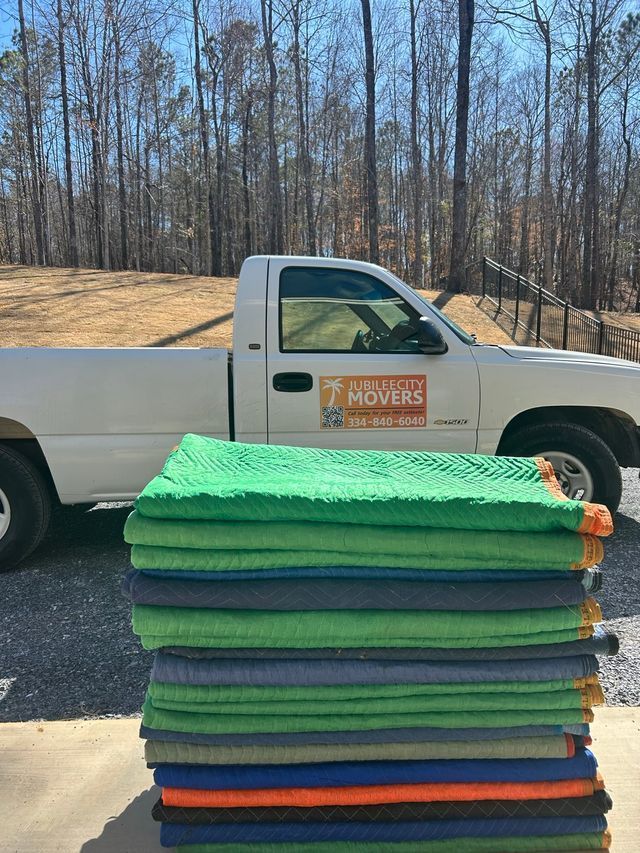 Stack of folded packing protective  towels in front of a white moving truck parked outdoors