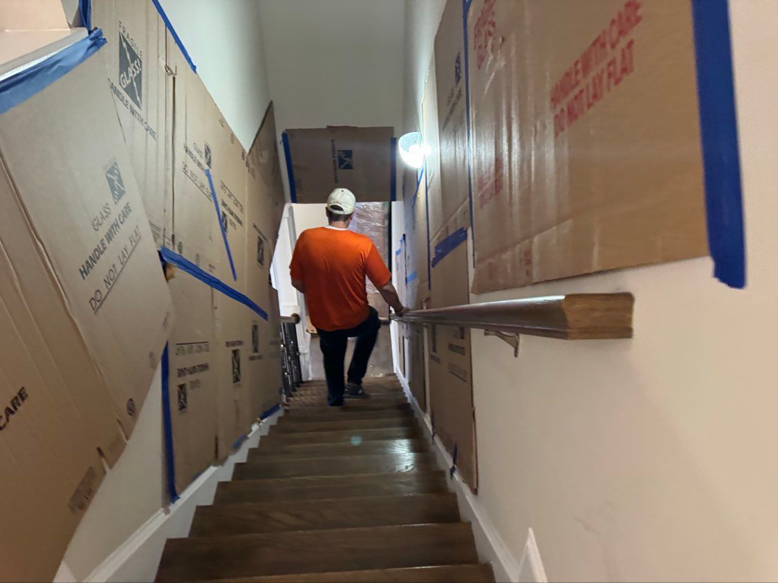 Worker in orange shirt going down the stairs lined with cardboard-covered walls