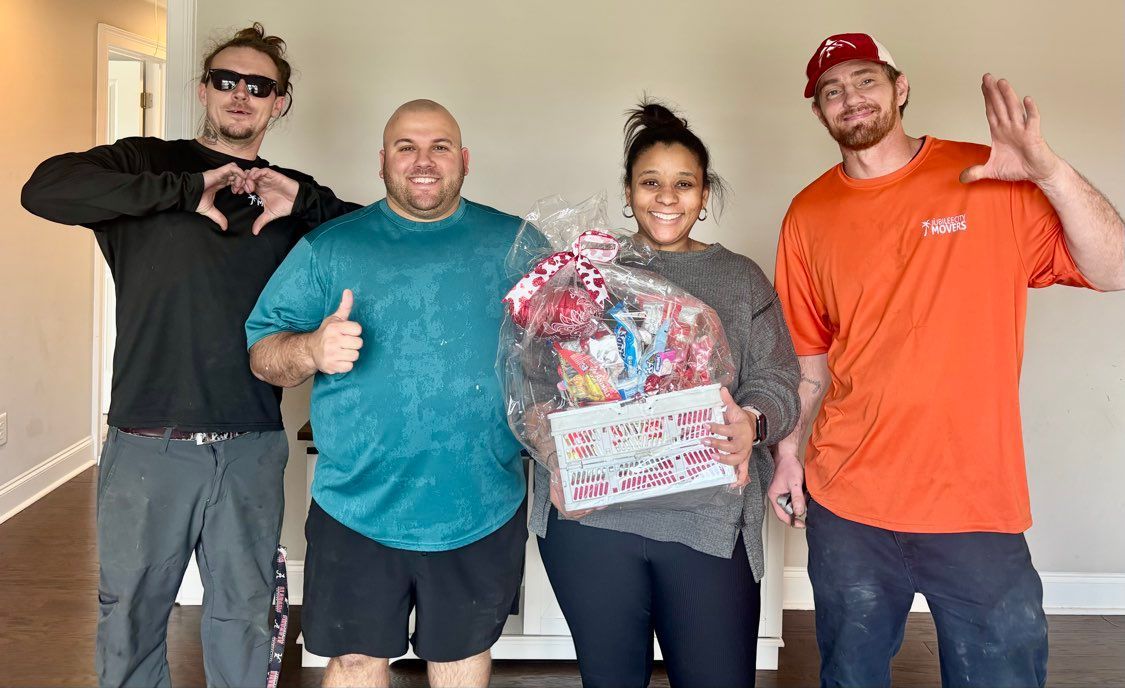 Jubilee City Movers staff posing with clients holding a wrapped gift basket
