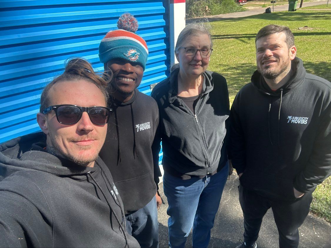 Four people smiling outdoors near a blue garage door