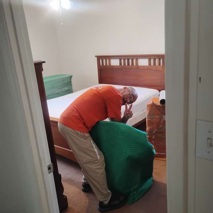 Person in a bedroom posing with a peace sign