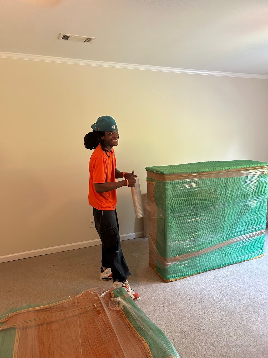 Person in orange shirt wrapping a large object