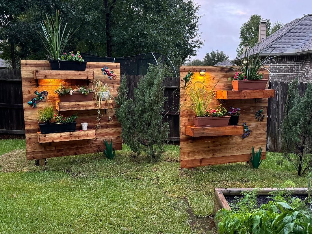 Two wooden pallet vertical gardens with plants on a grassy lawn.