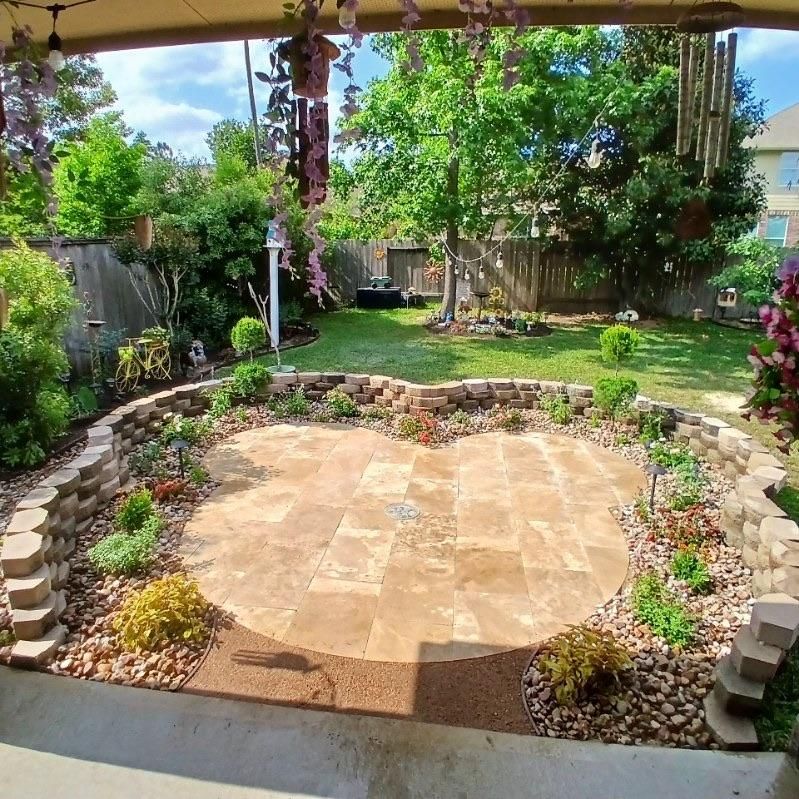 Backyard patio with heart-shaped stone platform surrounded by flowers and greenery.