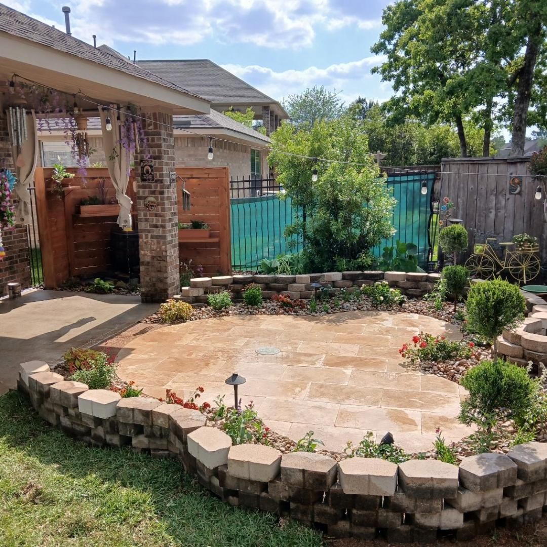 A backyard patio with a low brick wall, plants, and a wooden structure.