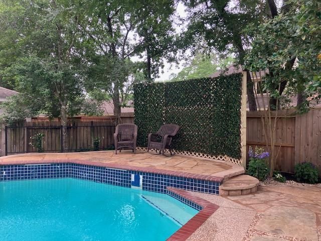 Poolside patio with two chairs and a green privacy wall.