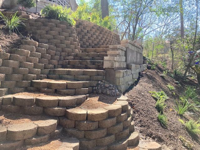 Stone steps built into a hillside with retaining walls and surrounding plants.