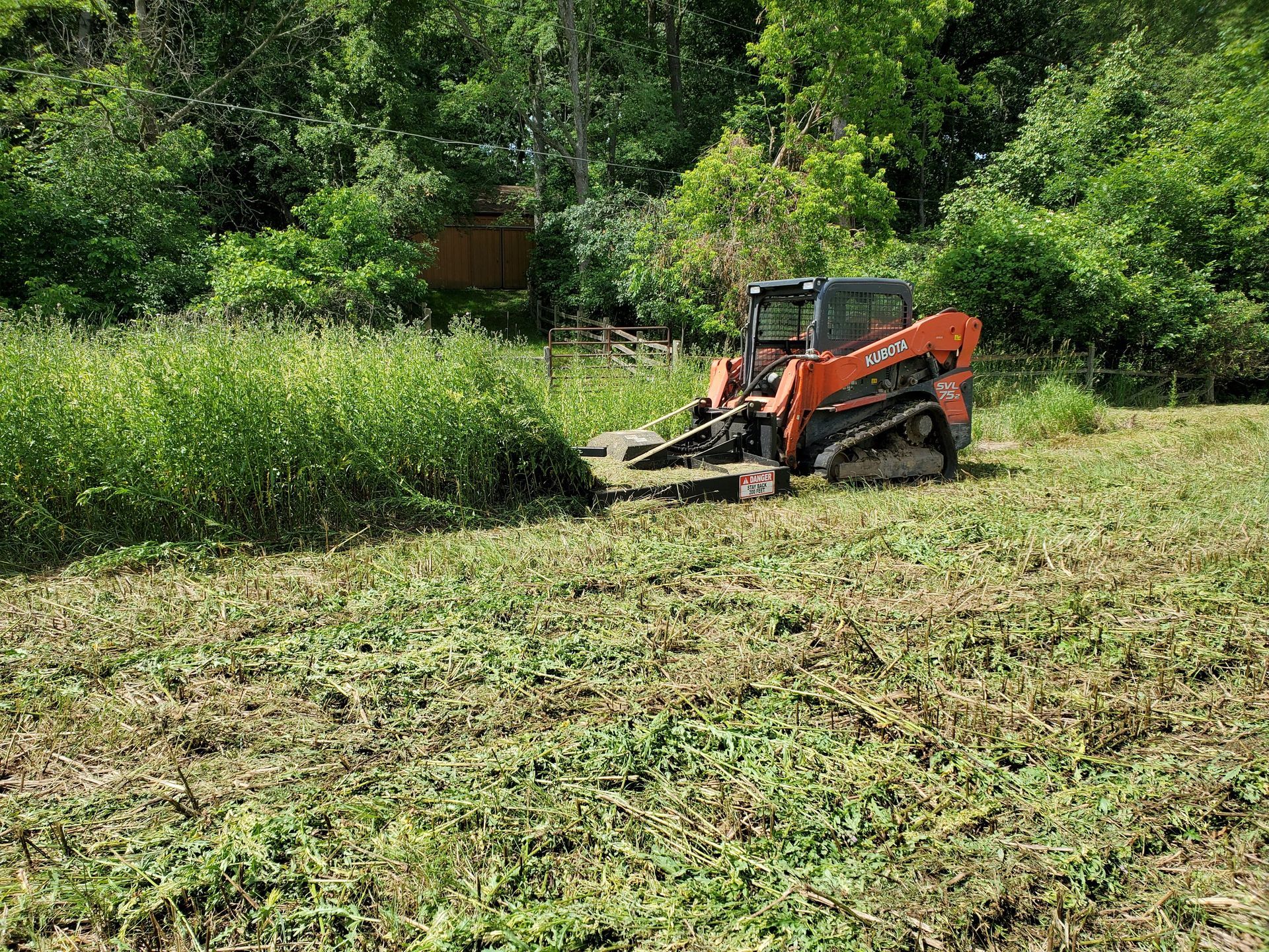 A bulldozer is cutting grass in a field.