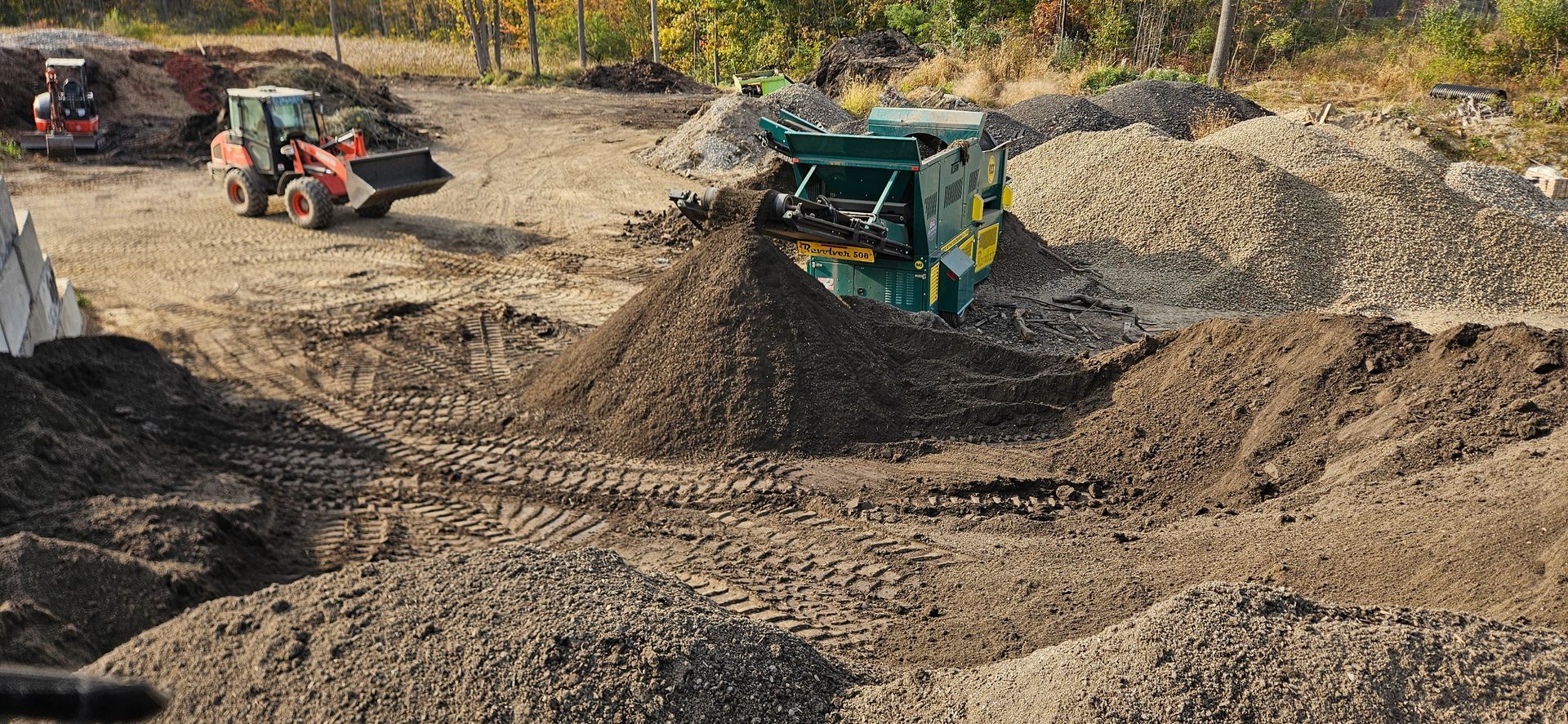 A large pile of dirt and rocks with a tractor in the background.