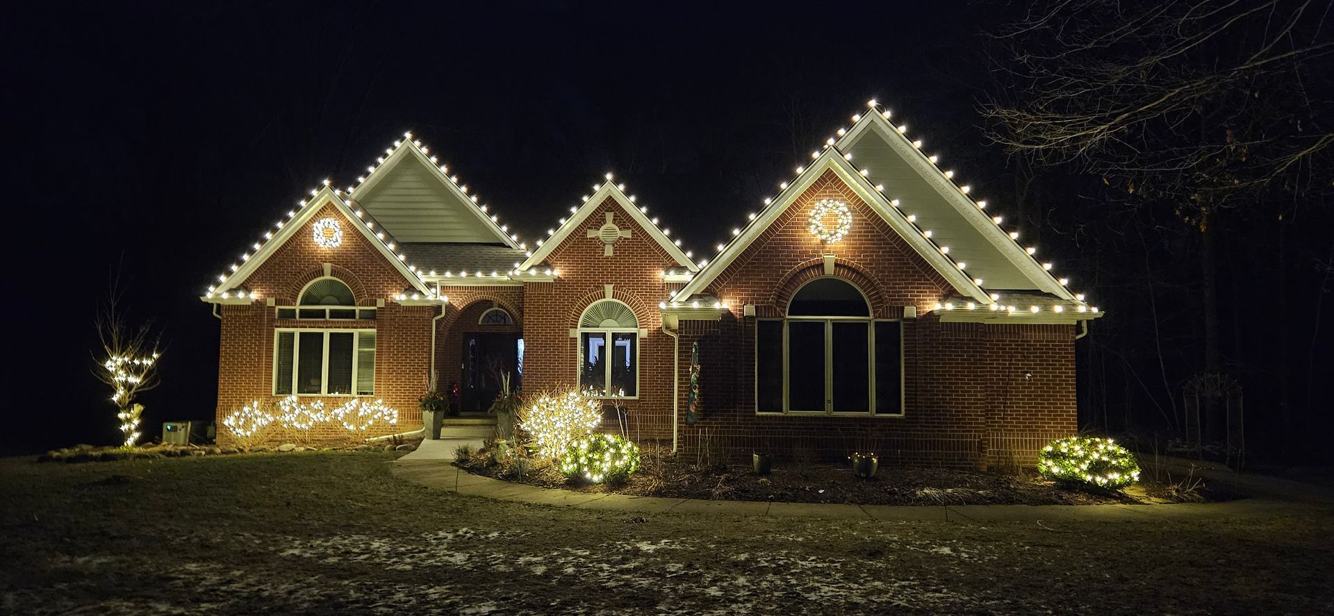 A brick house is decorated with christmas lights at night.