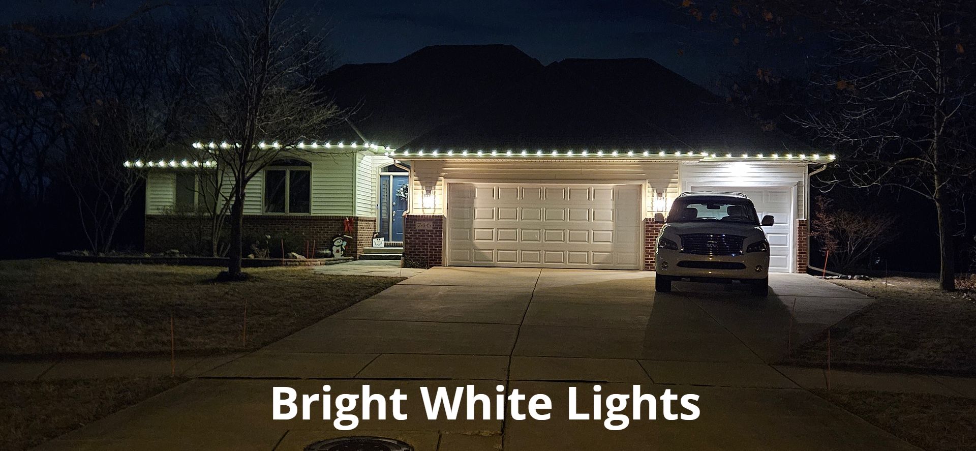 A car is parked in front of a house with bright white lights.