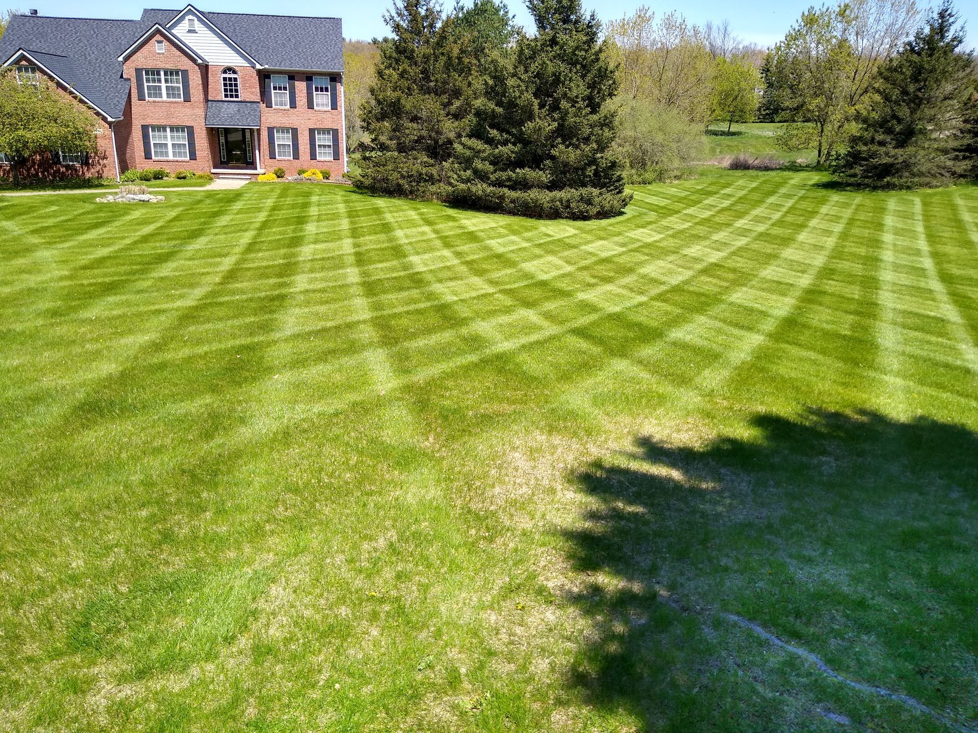 A large brick house with a lush green lawn in front of it.