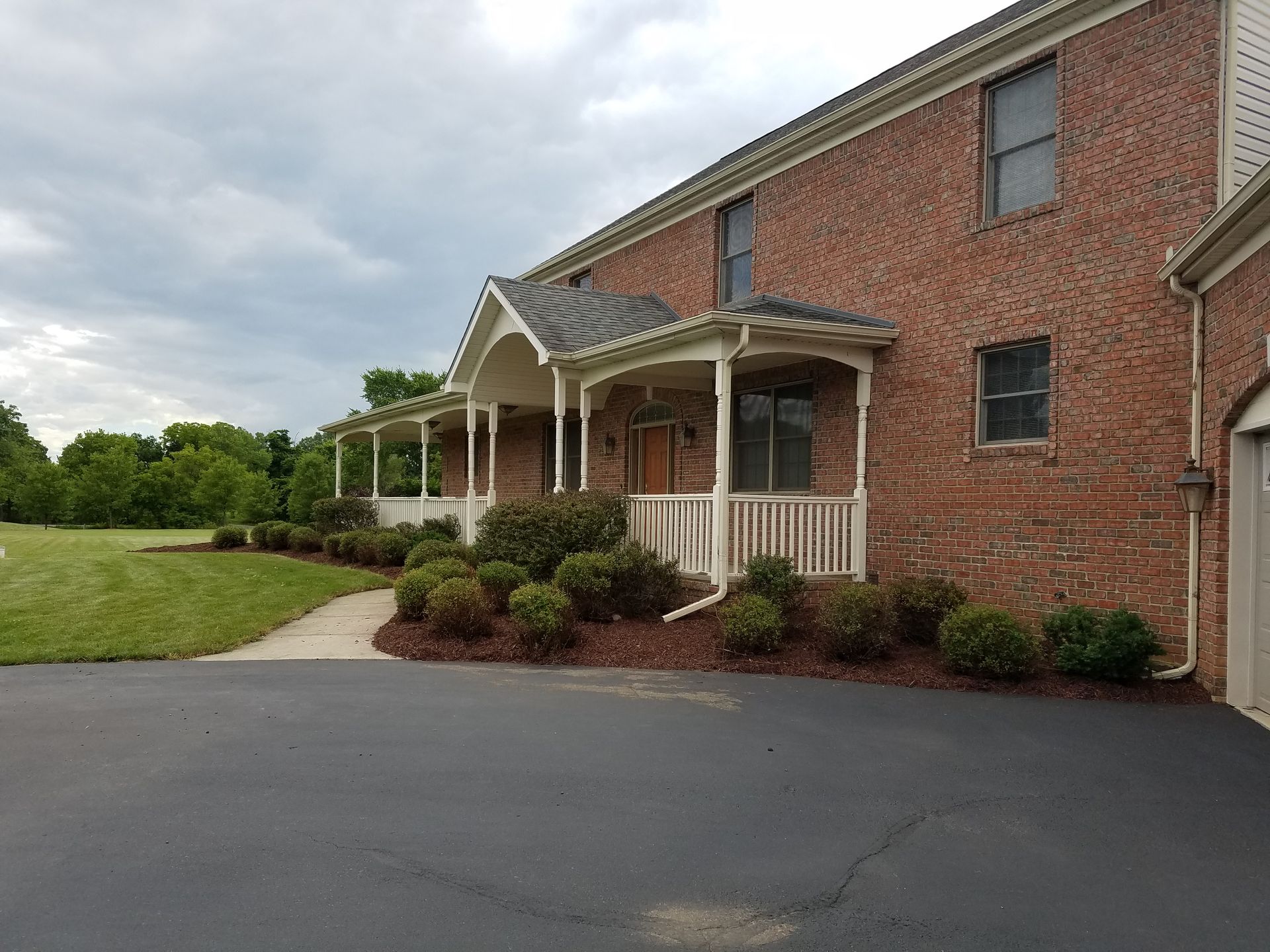 A large brick house with a porch and a driveway