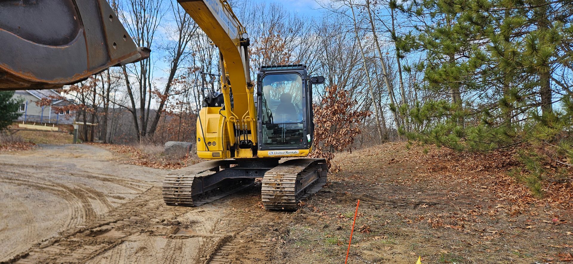 A yellow excavator is digging a hole in a yard.