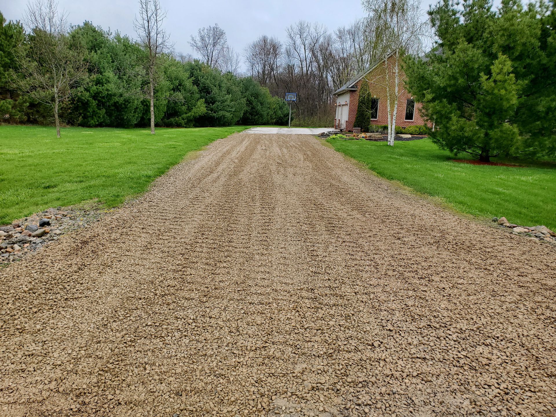 A gravel driveway leading to a house in a grassy field.