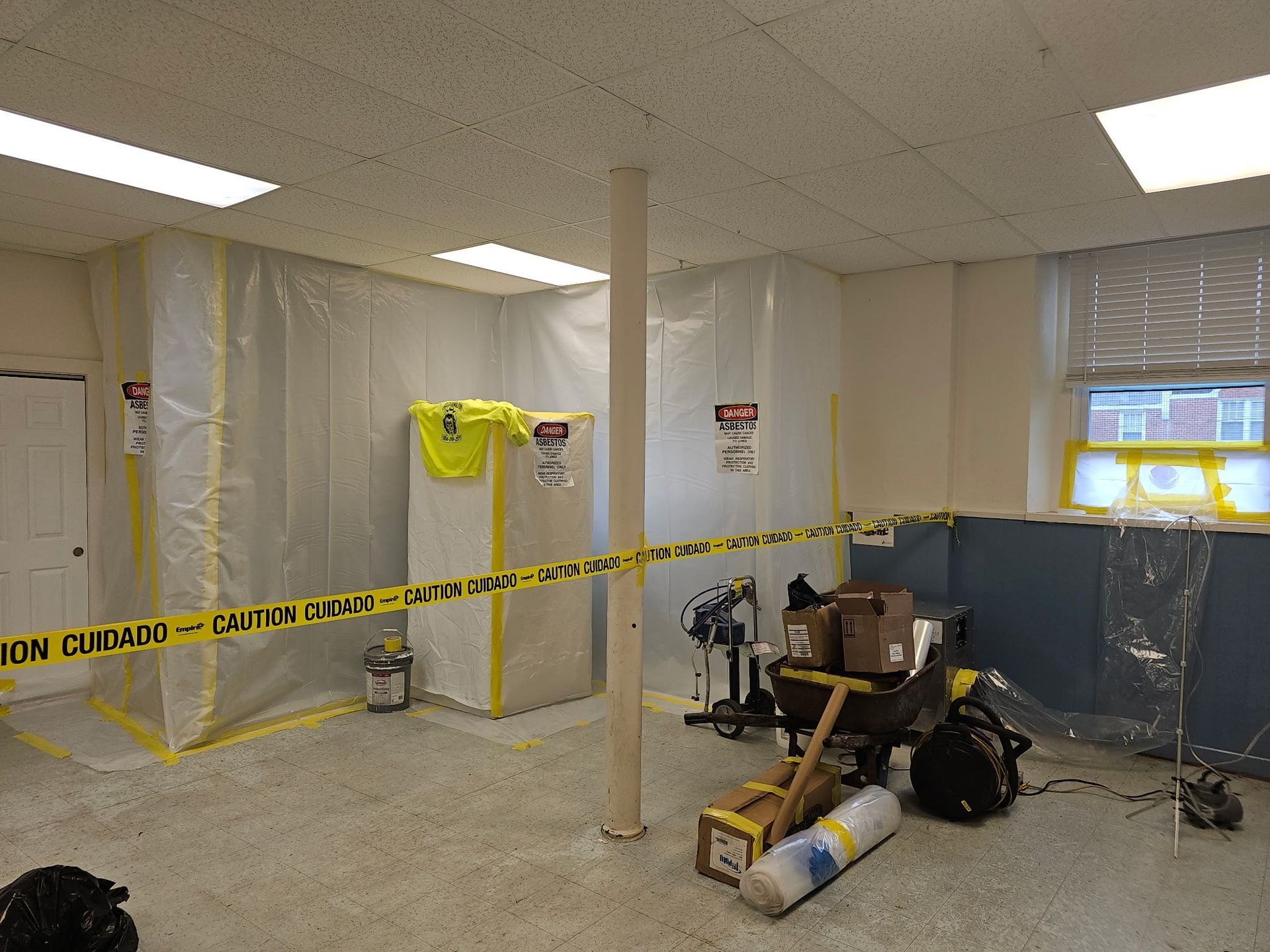 Room with containment barriers, caution tape, and equipment, indicating a potential hazardous materials cleanup.