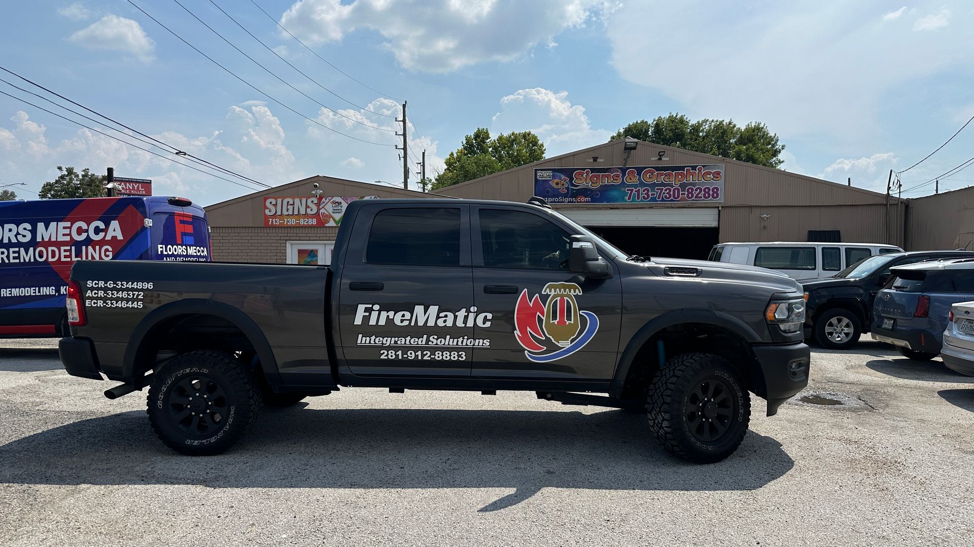 Dark gray FireMatic truck parked in front of a building. The truck has large black wheels.