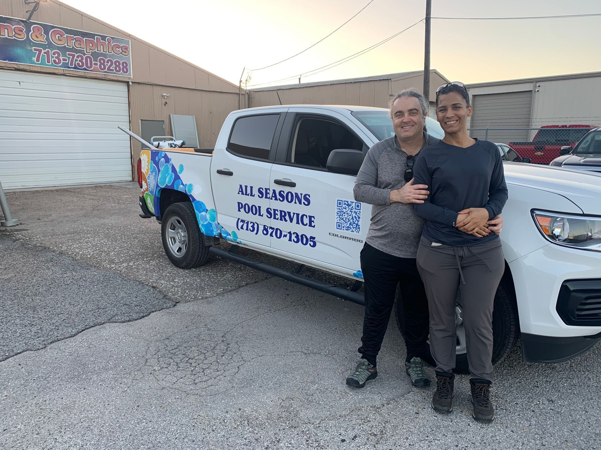 Two people stand beside a white truck with 