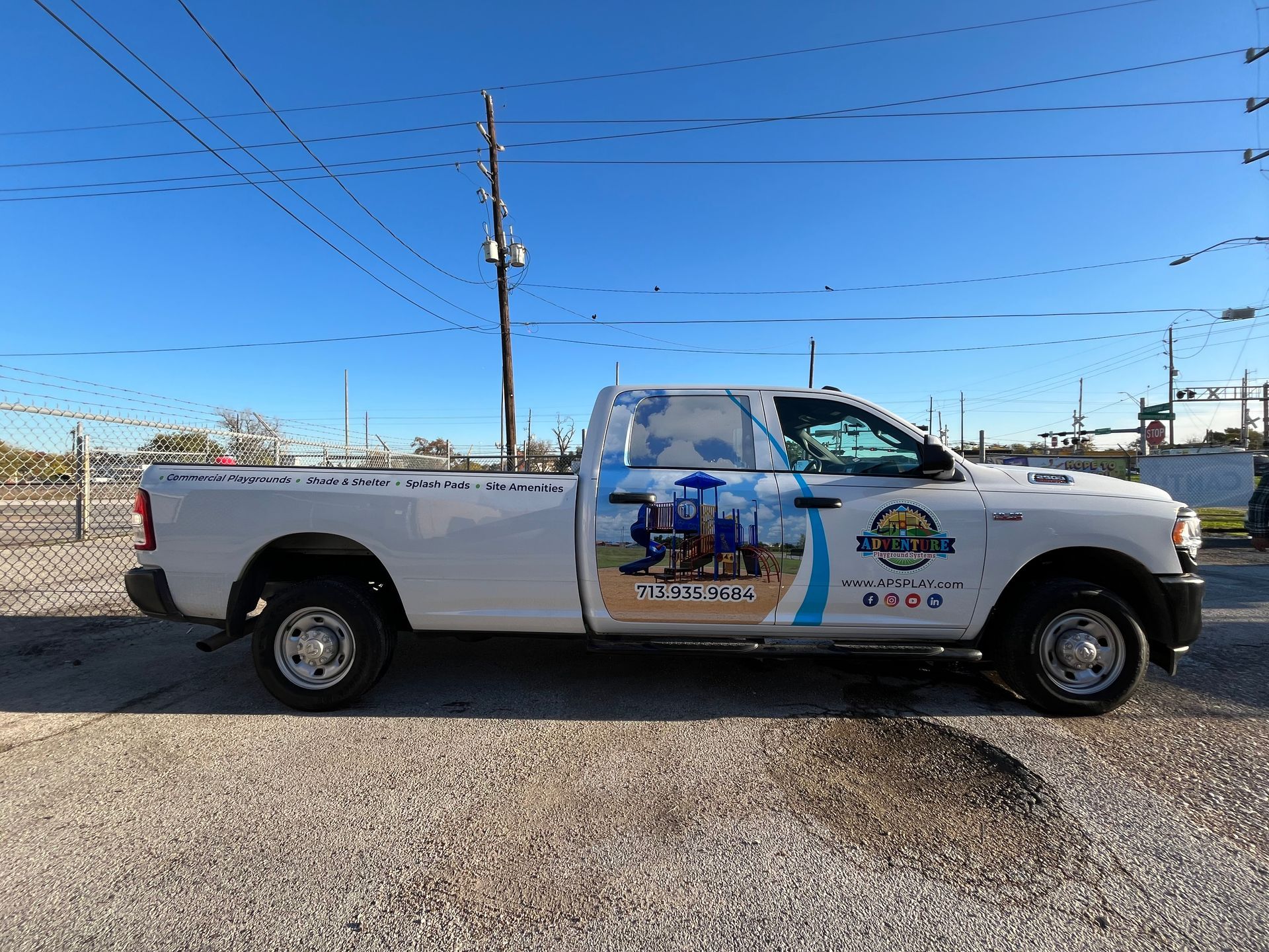 White work truck with business logo on the side, parked outside. Blue sky background.