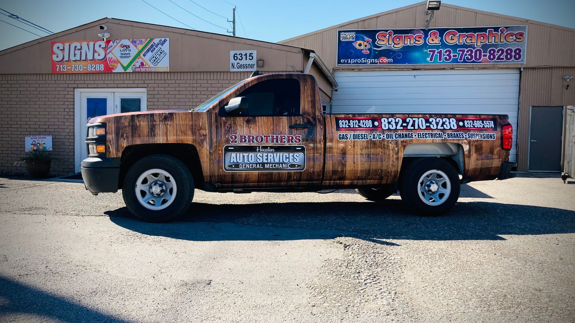 Brown wood-wrapped pickup truck parked in front of a building with sign.